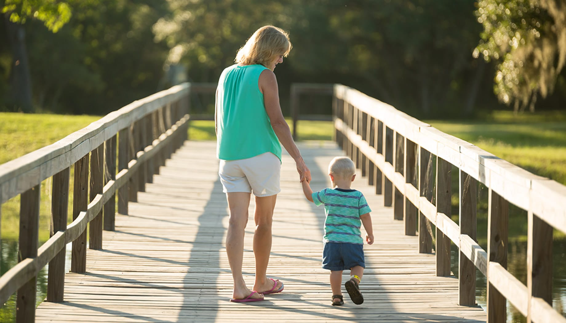 mother-son-walking Mother and son holding hands and walking along a wooden bridge.