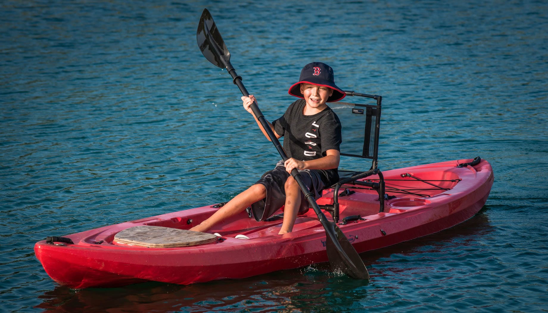 kayaking-on-pond Boy kayaking in a red kayak on a pond.