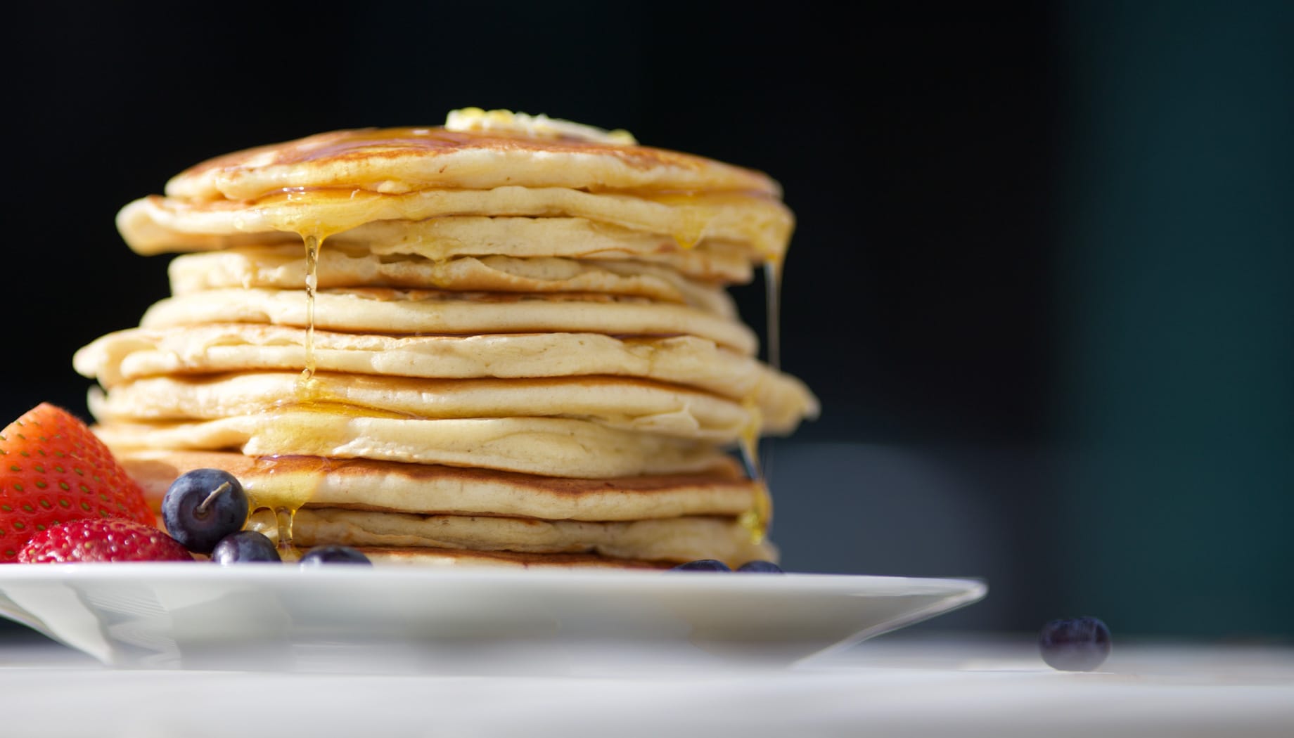pancakes Stack of fluffy pancakes with butter on top and served with strawberries and blueberries.