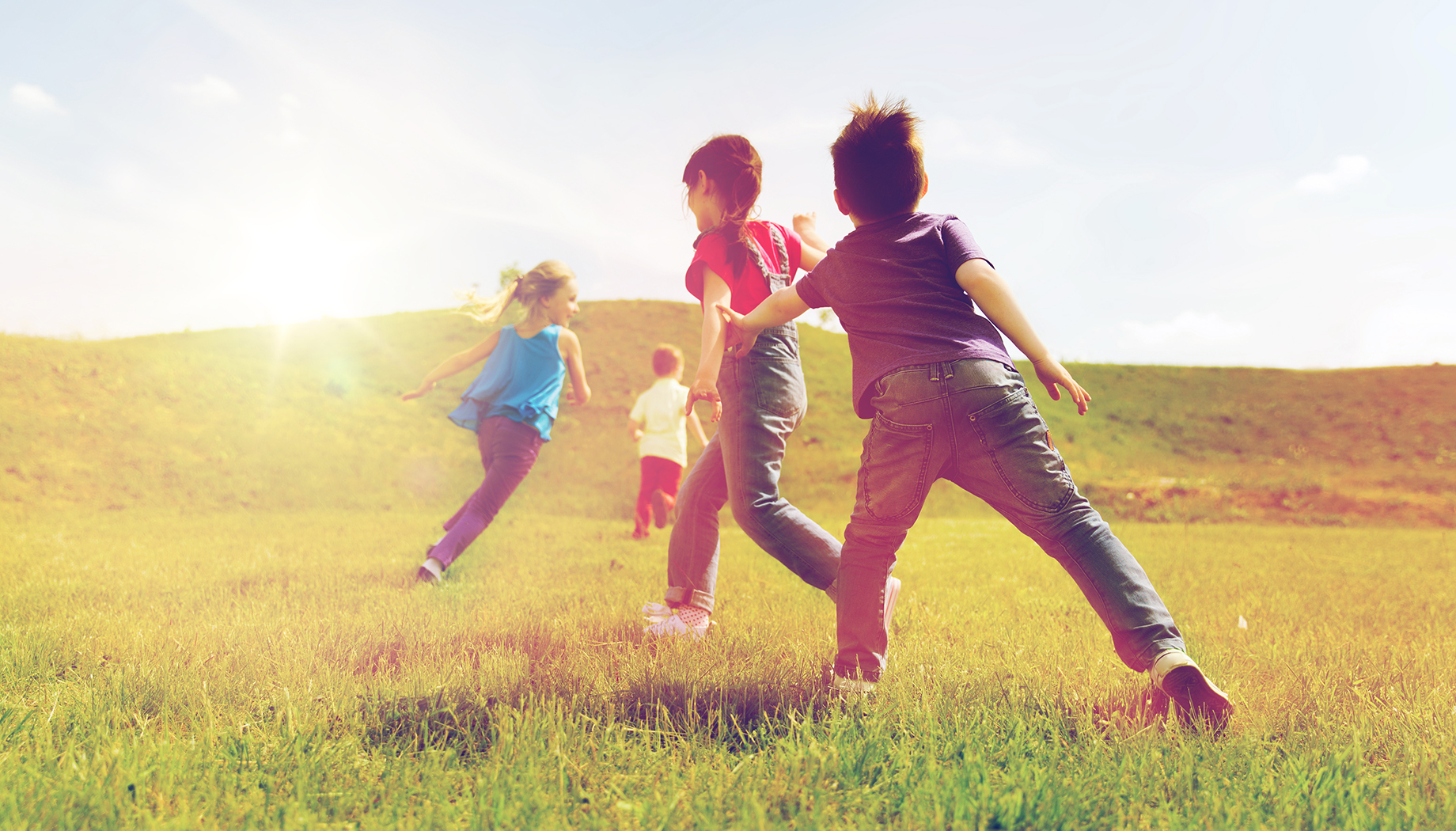 group of happy kids running outdoors Group of kids playing a game of tag in a grassy field.